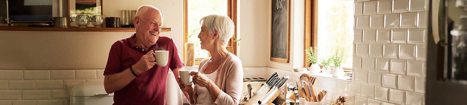 Retired couple enjoying coffee in their kitchen.
